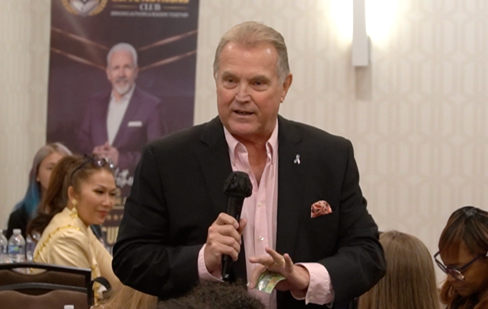 Scott Schilling speaking with a microphone in hand at a live event in Philadelphia